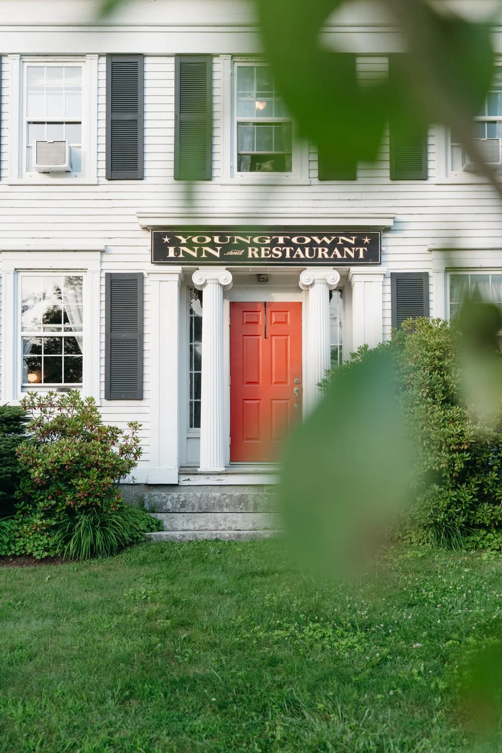 Front view of Youngtown Inn and Restaurant featuring a red door and white siding.