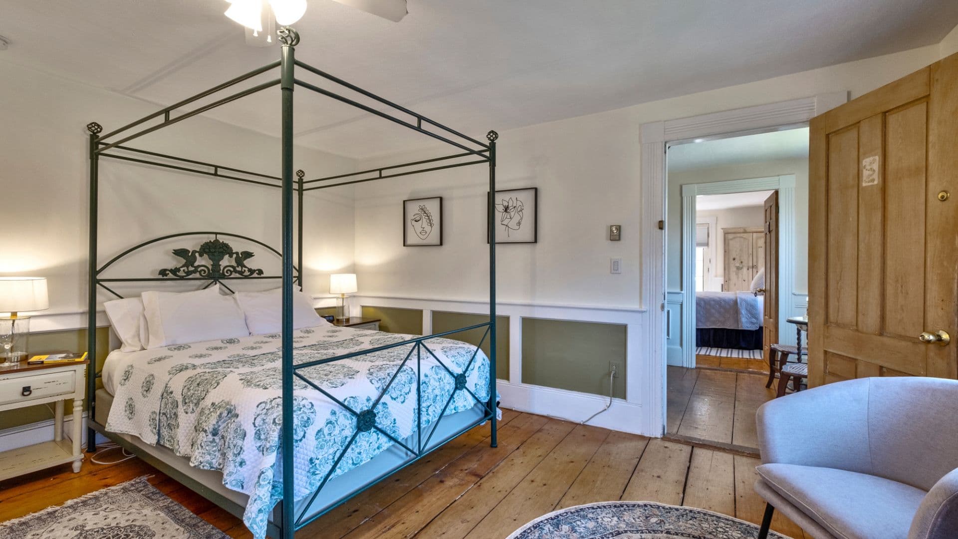 A cozy bedroom featuring a canopy bed, hardwood floors, and a doorway leading to another room.